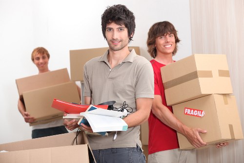 Removal workers carrying furniture through a Hampstead property entrance